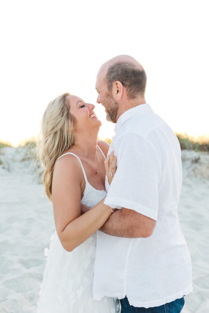 Couple laughs in the sand dunes for their anniversary photos with their New Smyrna Beach Photographer