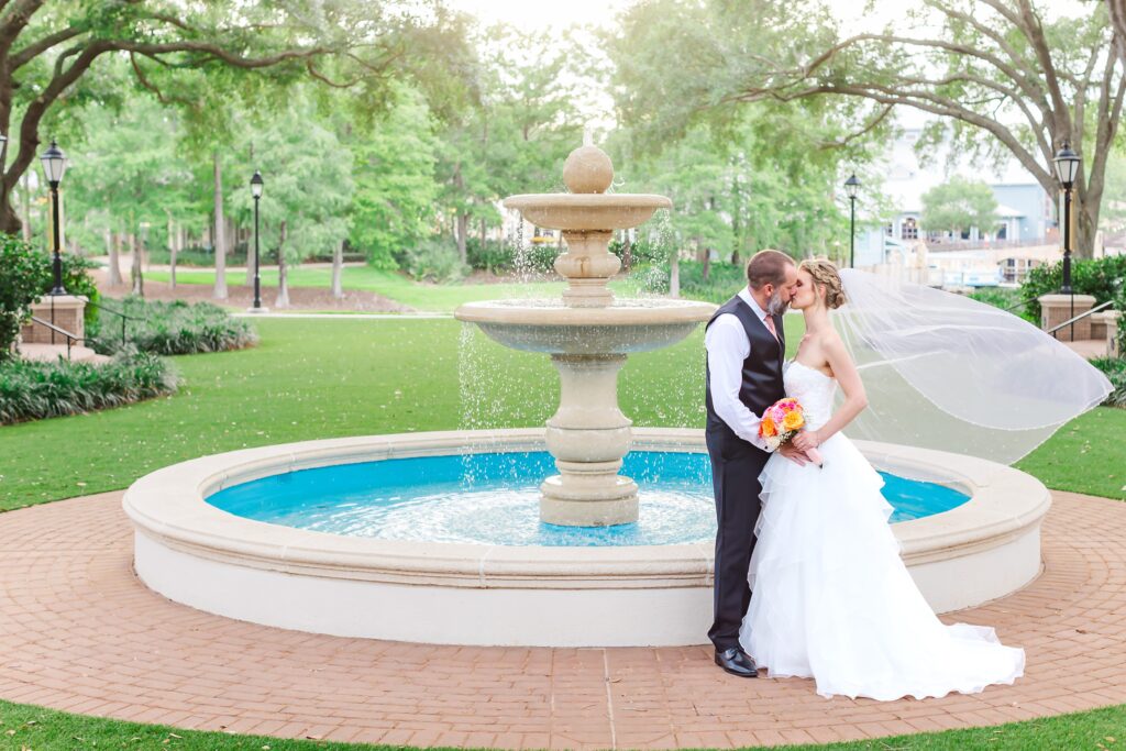 Bride and Groom kiss while Bride's veil flies in front of fountain after their Disney Elopement at Disney's Port Orleans Riverside Resort
