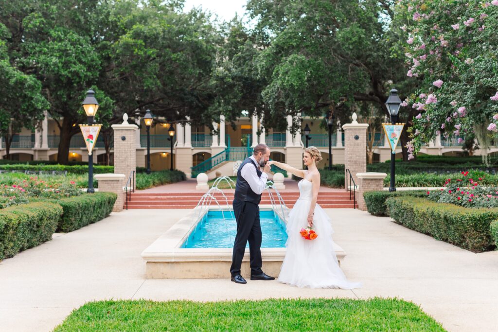 Groom kisses Bride's hand in front of fountain after their Disney Elopement at Disney's Port Orleans Riverside Resort