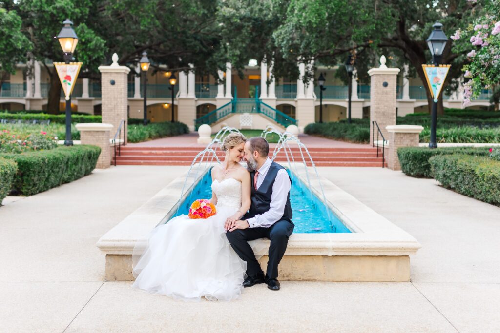 Bride and Groom sit in front of fountain after their Disney Elopement at Disney's Port Orleans Riverside Resort