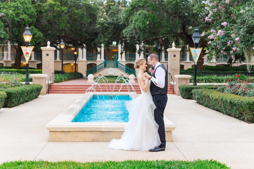 Bride and Groom hold hands in front of fountain after their Disney Elopement at Disney's Port Orleans Riverside Resort
