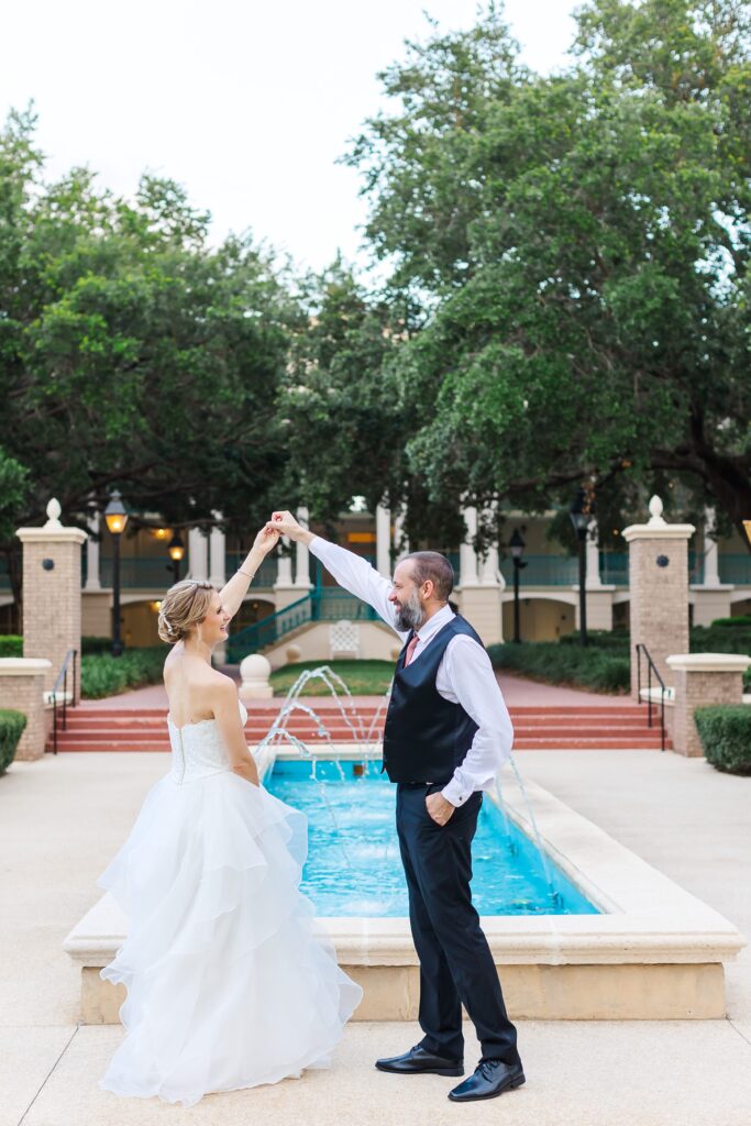 Groom twirls Bride as they dance in front of fountain after their Disney Elopement at Disney's Port Orleans Riverside Resort