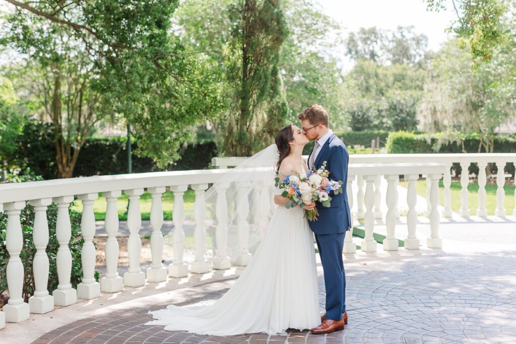 Bride and Groom kissing while veil flies at their Leu Gardens Wedding in Orlando, Florida