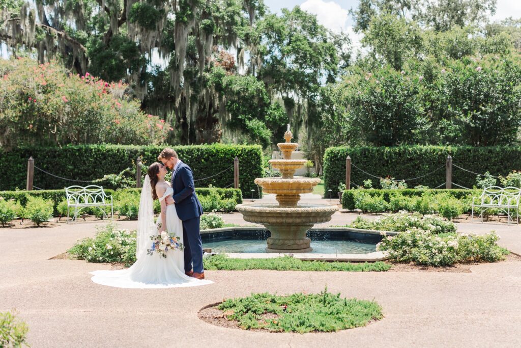 Groom dips Bride as they smile and laugh in front of fountain in Rose Garden at their Leu Gardens Wedding in Orlando, Florida