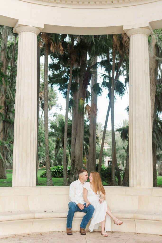 Couple snuggles together after proposal in front of the columns at Kraft Azalea Garden in Orlando, Florida