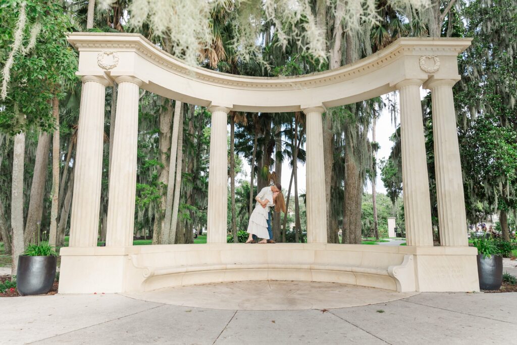 Guy dips girl and kisses her after proposal in front of the columns at Kraft Azalea Garden in Orlando, Florida