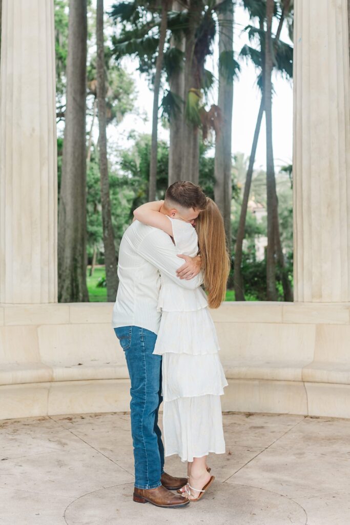 Couple hugs after proposal in front of the columns at Kraft Azalea Garden in Orlando, Florida