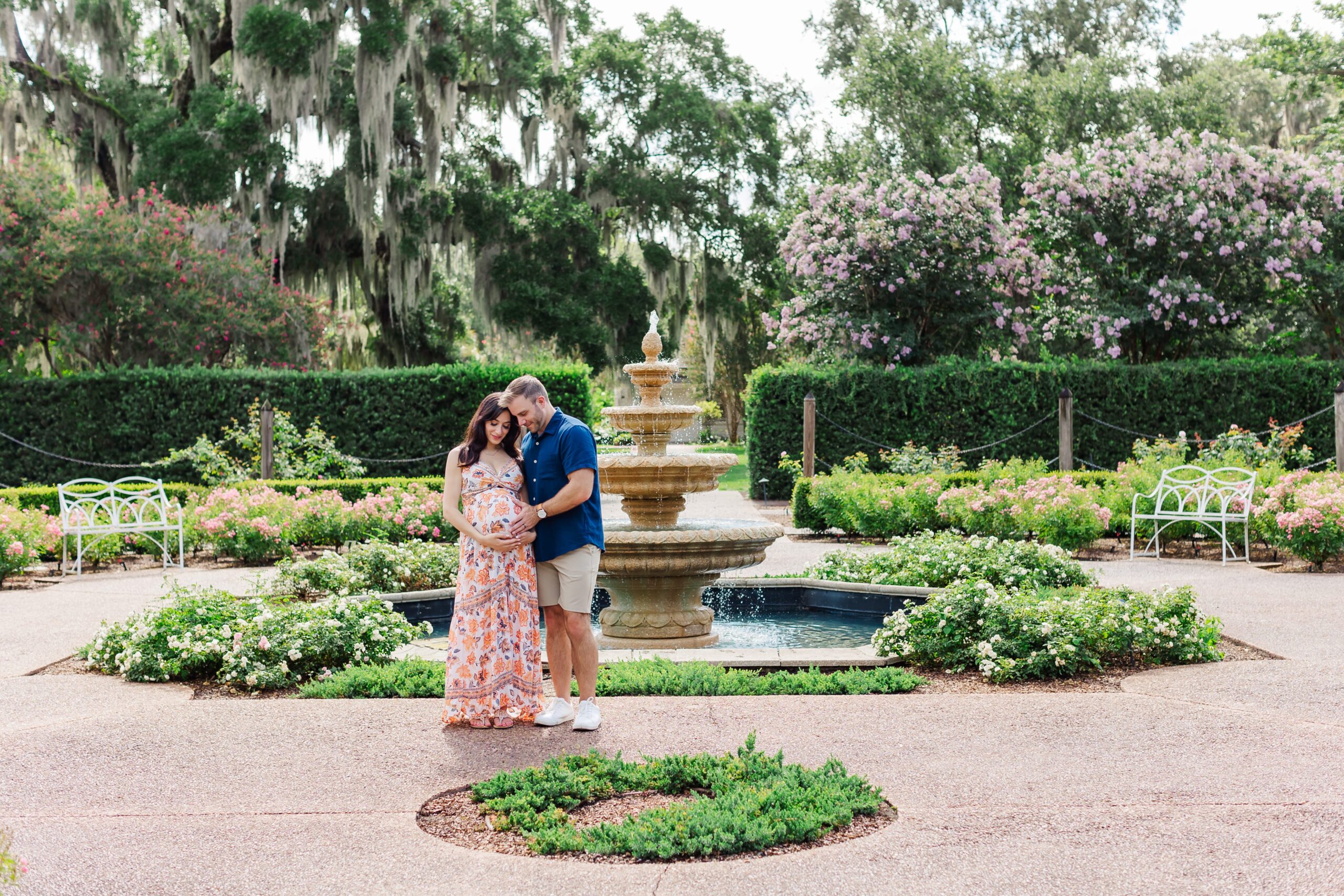 Couple stands in front of fountain in the rose garden for their Orlando Maternity Photos at Leu Gardens