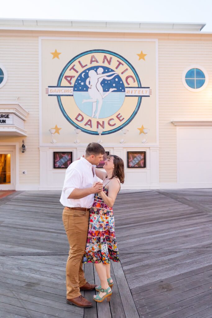 Couple dances in front of Atlantic Dance Hall for their Disney Engagement Photos at The Boardwalk