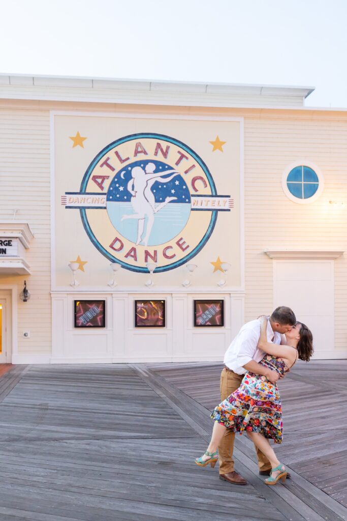 Guy dips and kisses girl in front of Atlantic Dance Hall for their Disney Engagement Photos at The Boardwalk