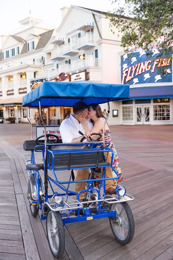 Couple kisses on surray bike for their Disney Engagement Photos at The Boardwalk