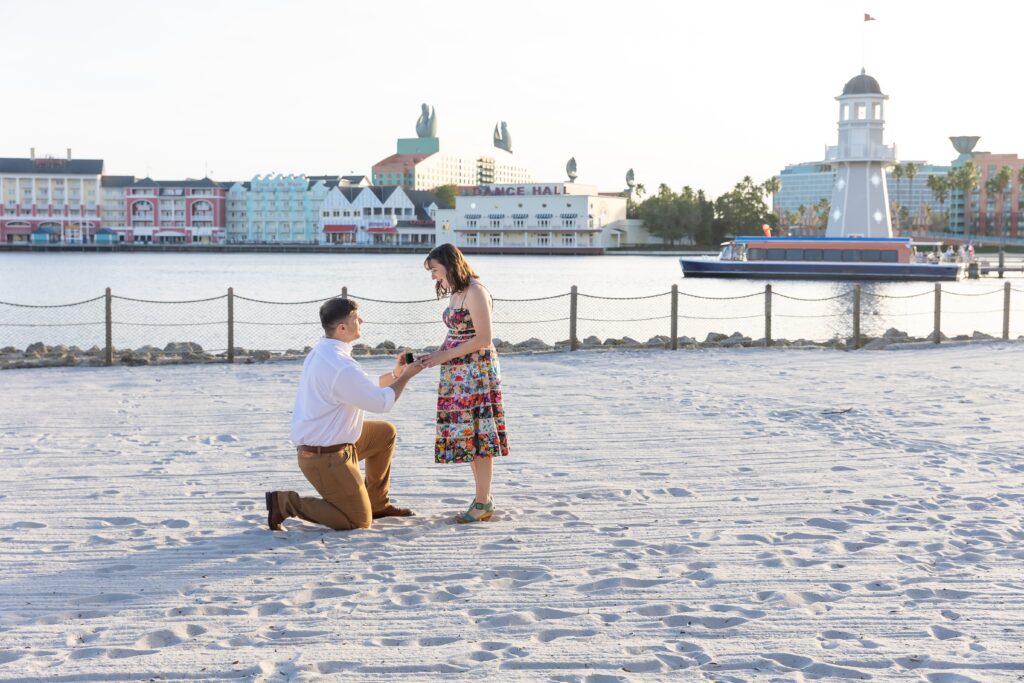 Guy proposes to girl in front of lighthouse on the beach at Disney's Beach Club Resort for their engagement photos