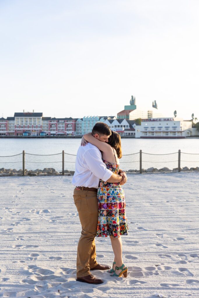 Couple hugs after their proposal on the beach at Disney's Beach Club Resort for their engagement photos