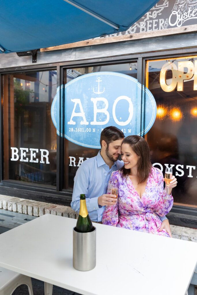 Couple kisses with champagne toast for their engagement photos at Atlantic Beer and Oyster on Park Ave in Winter Park, Florida