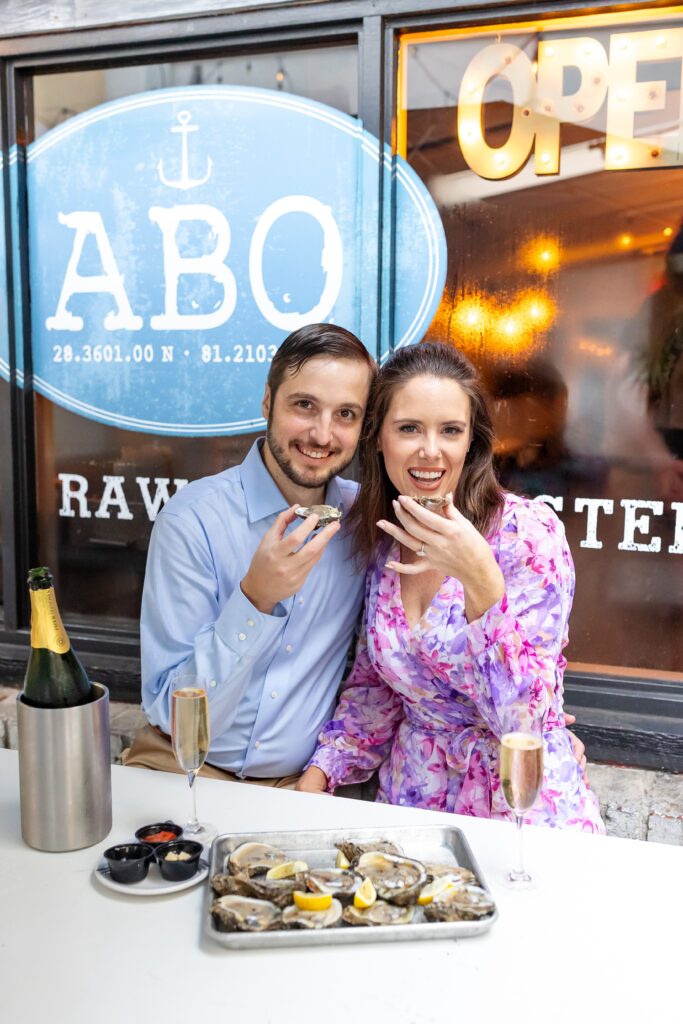 Couple celebrates with champagne and oysters for their engagement photos at Atlantic Beer and Oyster on Park Ave in Winter Park, Florida