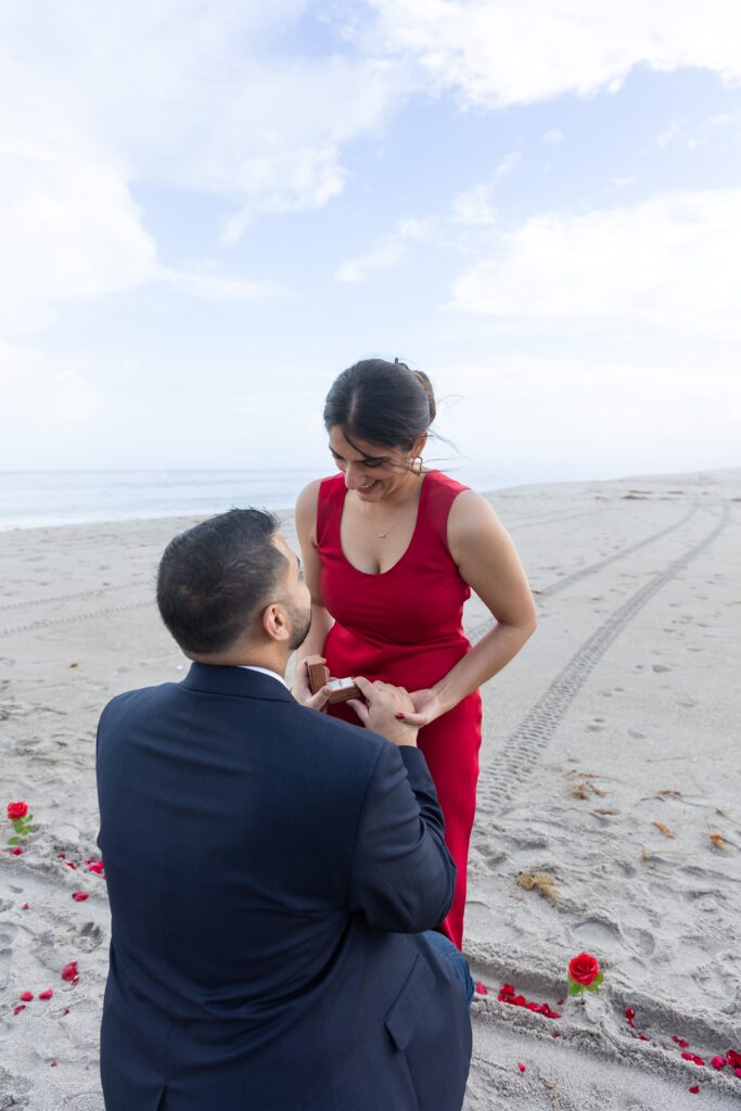 Guy proposes in front of the ocean at Lori Wilson Park for their engagement photos in Cocoa Beach, Florida