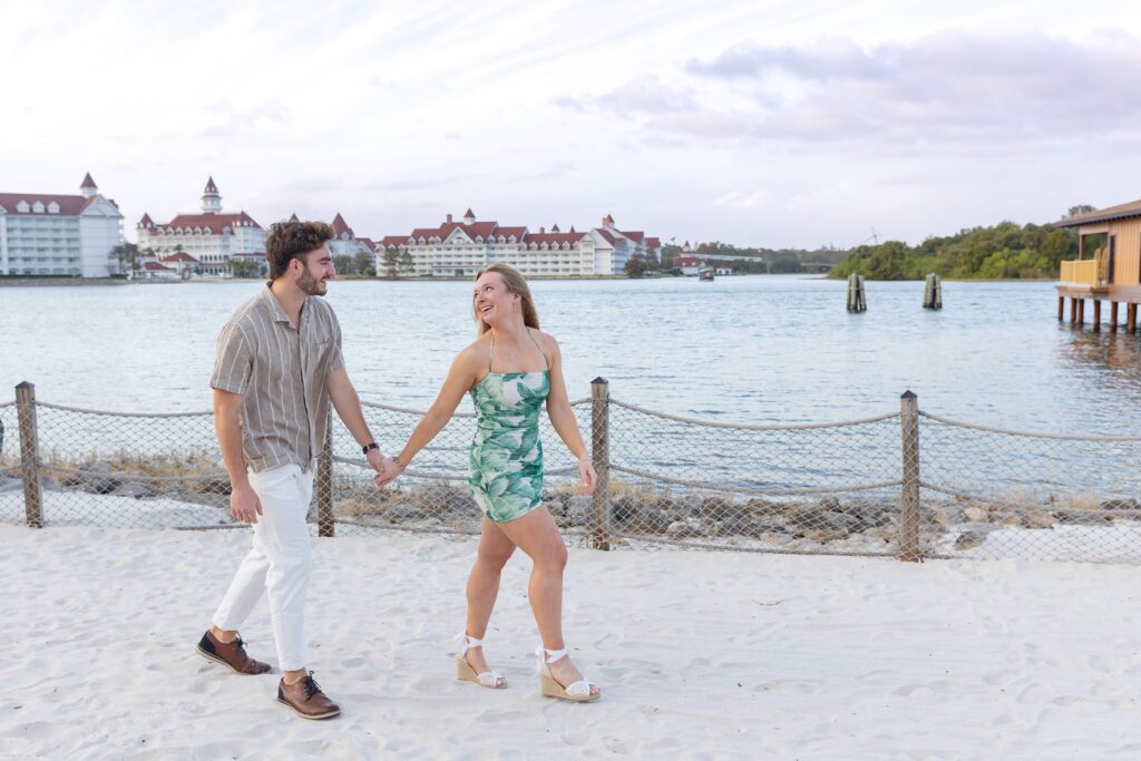 Couple holds hands and walks on the beach after their proposal at Disney's Polynesian Resort in Orlando, Florida