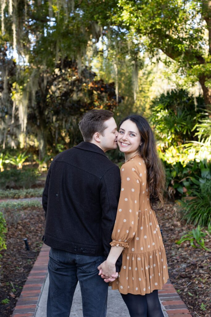 Guy kisses girls cheek for their engagement photos at Cypress Grove Park in Orlando, Florida