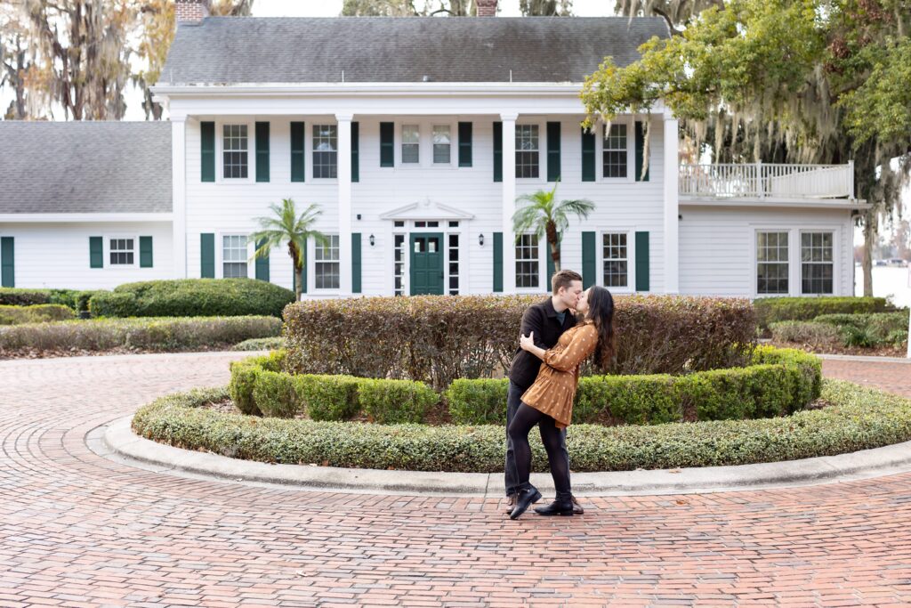 Guy dips and kisses girl in front of Cypress Grove Estate House for their engagement photos at Cypress Grove Park in Orlando, Florida