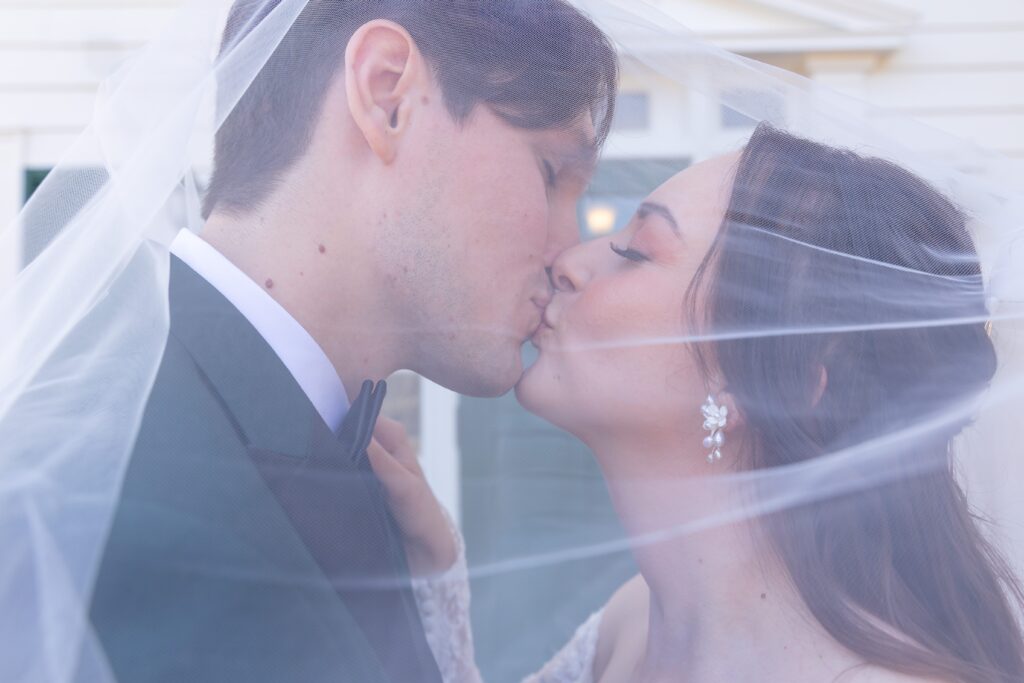 Bride and Groom kiss under veil at their micro wedding at Cypress Grove Estate House in Orlando, Florida