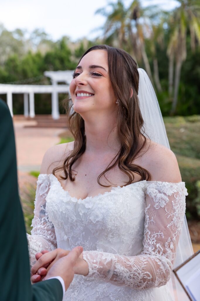 Bride smiles as groom says his vows at his micro wedding at Cypress Grove Estate House in Orlando, Florida