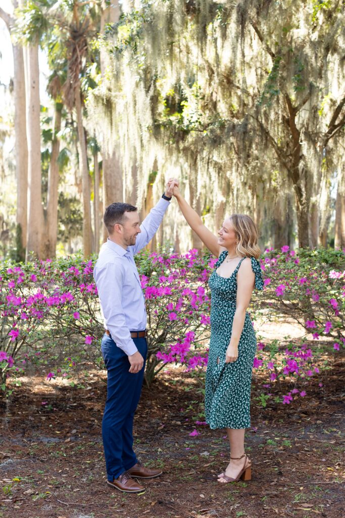 Guy twirls girl in front of purple azaleas for the engagement photos at Kraft Azalea Garden in Orlando, Florida