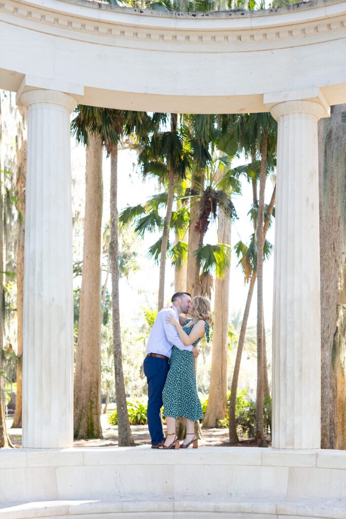 Couple kisses on top of columns for their engagement photos at Kraft Azalea Garden in Orlando, Florida