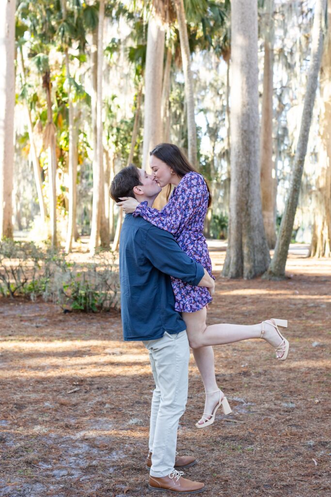 Guy lifts girl and kisses her for their engagement photos at Kraft Azalea in Orlando, Florida