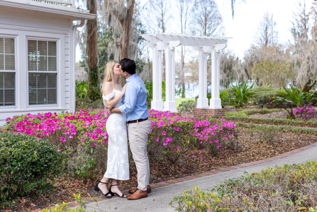 Couple kisses in front of purple flowers for their engagement photos at Cypress Grove Park in Orlando, Florida