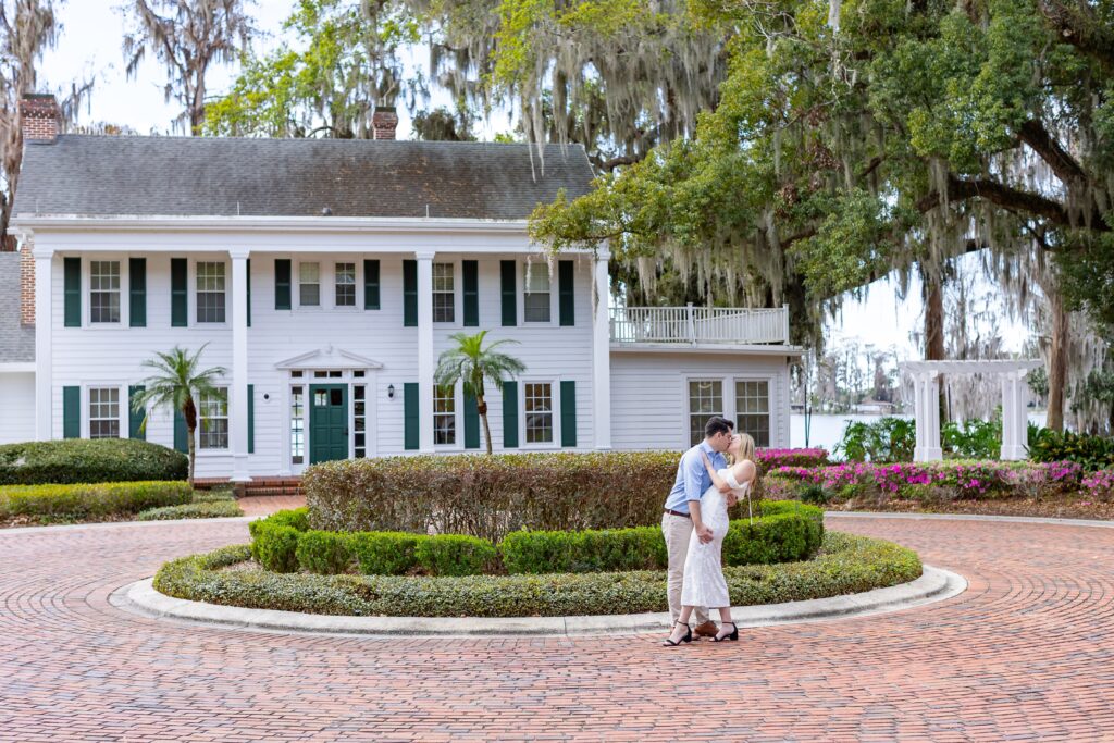 Guy dips and kisses girl in front of Cypress Grove Estate House for their engagement photos at Cypress Grove Park in Orlando, Florida