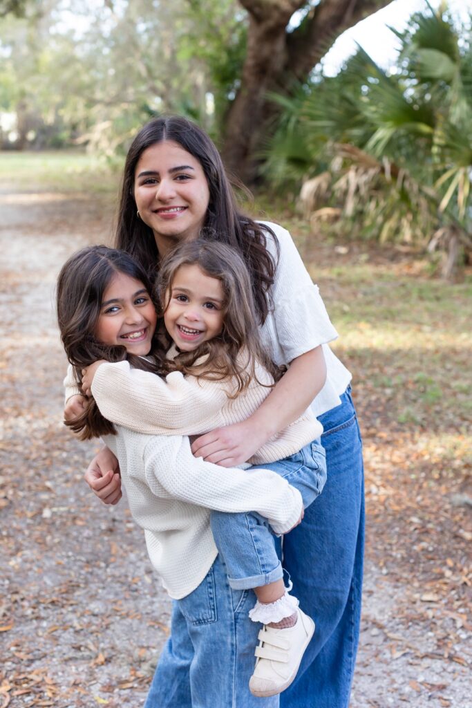 3 sisters hug for their family photos at Greenwood Lakes Park in Lake Mary, Florida with Orlando Family Photgrapher Amy Britton Photography