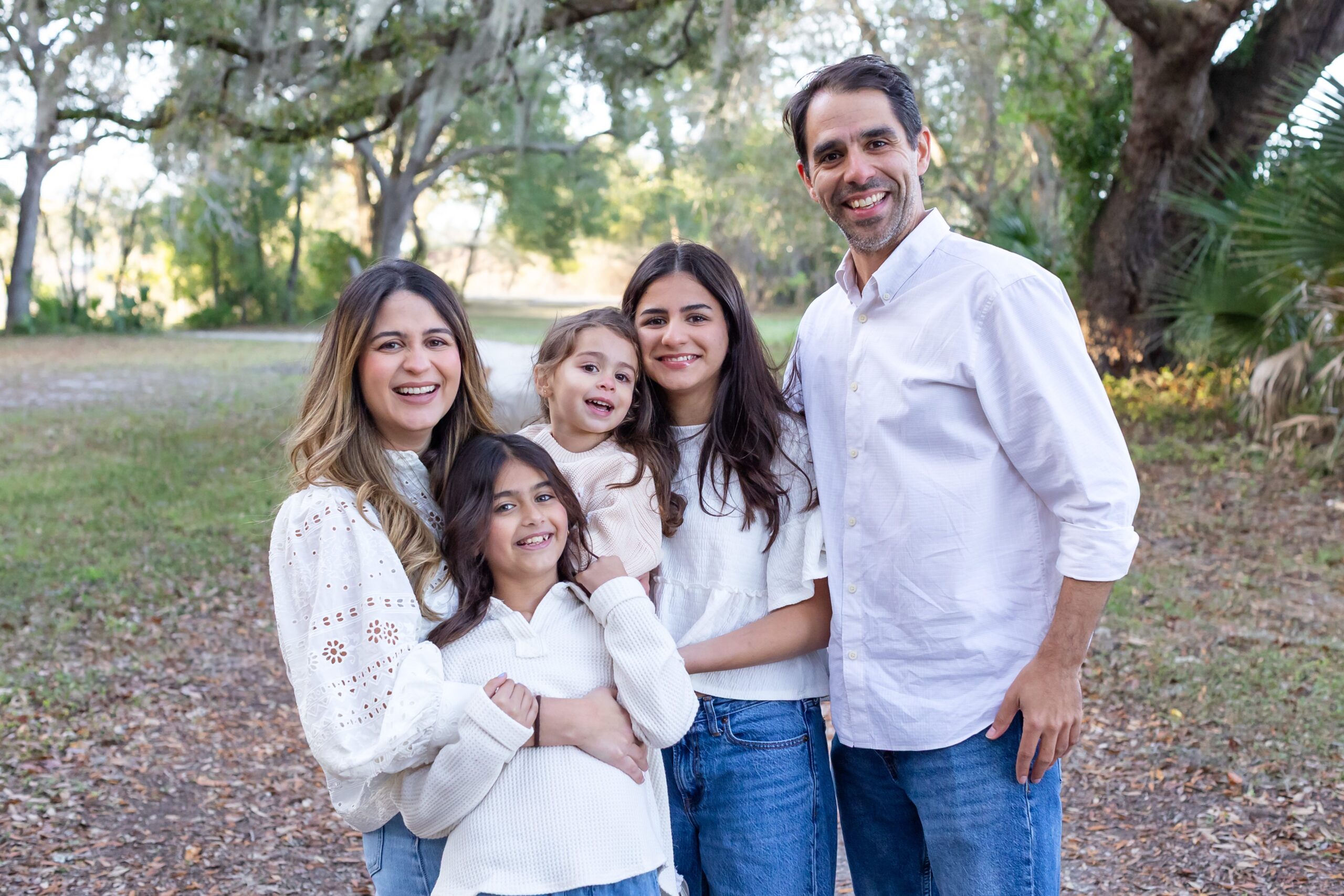 Family poses under spanish moss tree for their family photos at Greenwood Lakes Park in Lake Mary, Florida with Orlando Family Photgrapher Amy Britton Photography