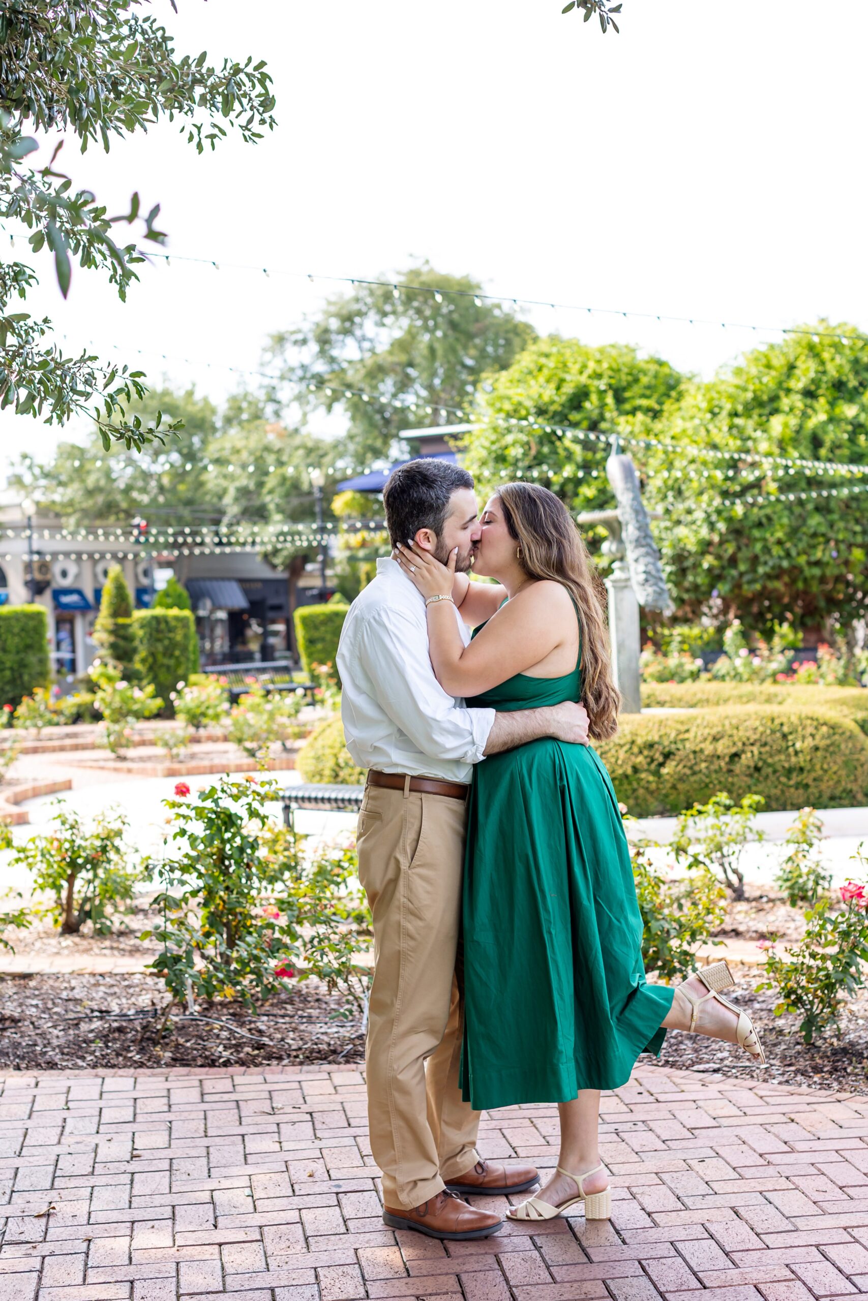 Guy kisses girl in front of the Rose Garden in Central Park Winter Park, Florida