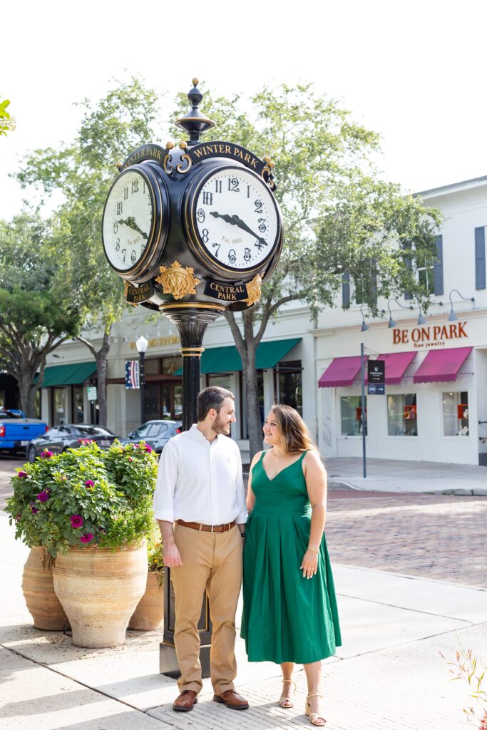 Couple holds hands along Park Ave in front of clock in Central Park Winter Park, Florida