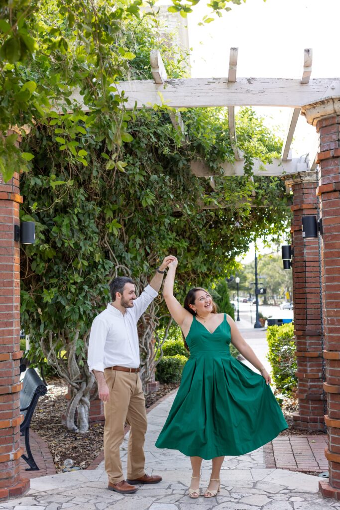 Guy twirls girl in front of the Rose Garden in Central Park Winter Park, Florida
