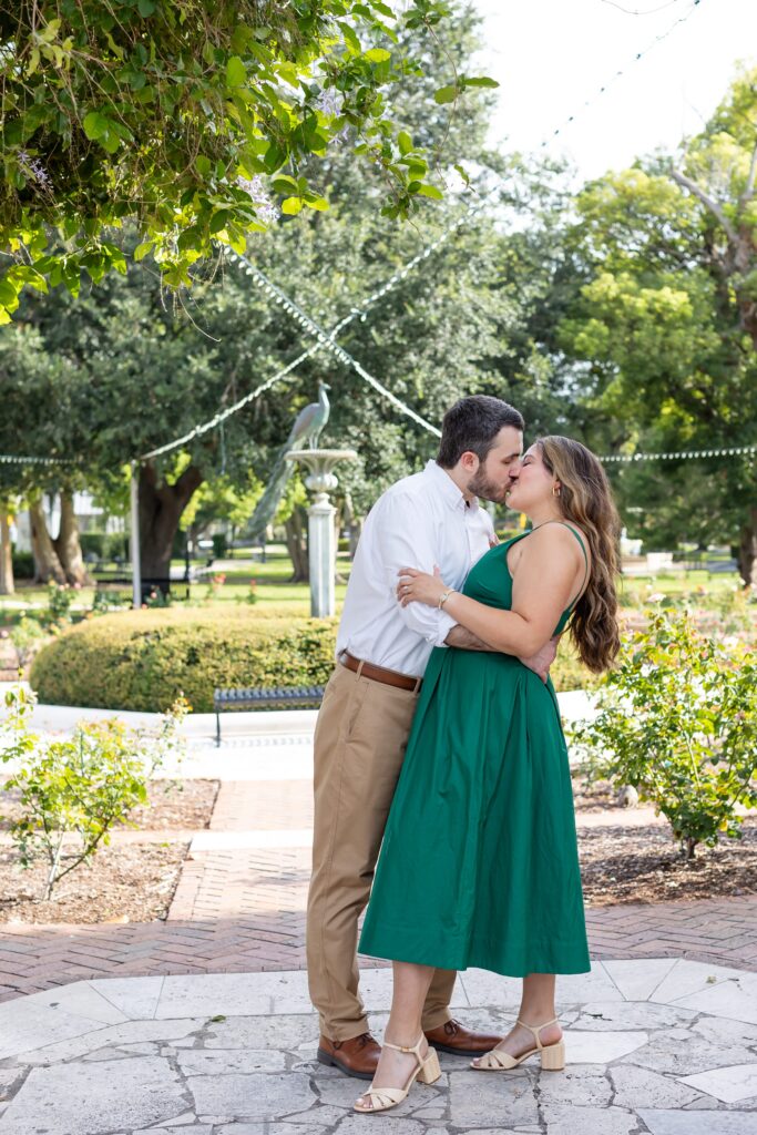 Guy kisses girl in front of the Rose Garden in Central Park Winter Park, Florida