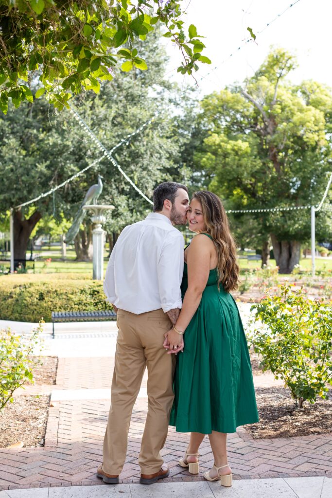 Guy kisses girl in front of the peacock fountain at the Rose Garden in Central Park Winter Park, Florida