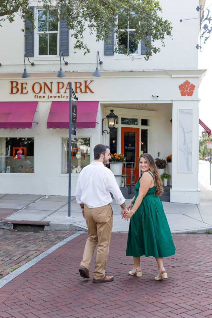 Couple holds hands and walks along Park Ave in Central Park Winter Park, Florida