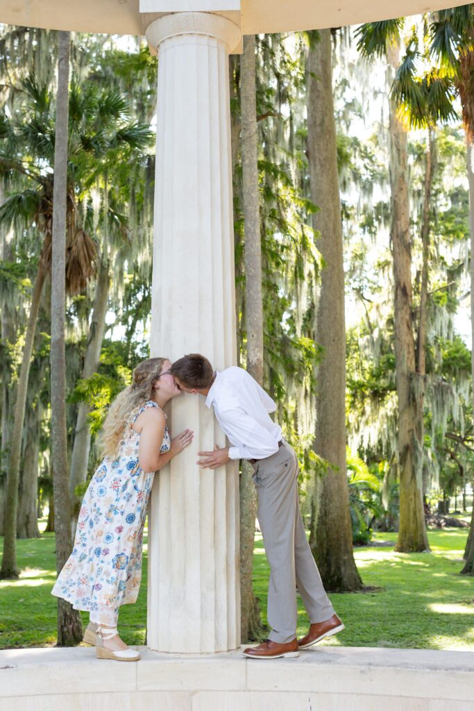 Couple kisses in front of Columns at Kraft Azalea Garden for their Winter Park Proposal