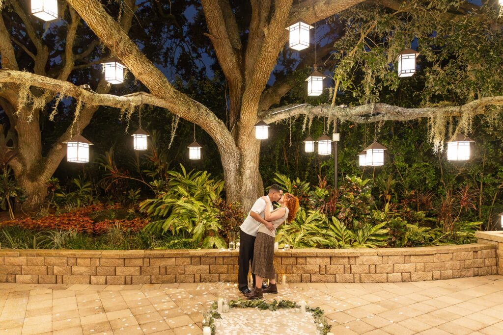 Couple kisses under tree with lanterns after their proposal at the Hyatt Regency Grand Cypress Resort Orlando Oak Terrace