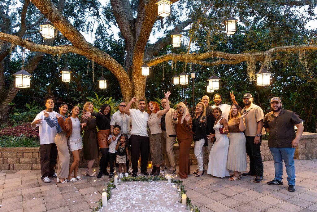 Couple celebrates with friends and family under tree with lanterns after their proposal at the Hyatt Regency Grand Cypress Resort Orlando Oak Terrace