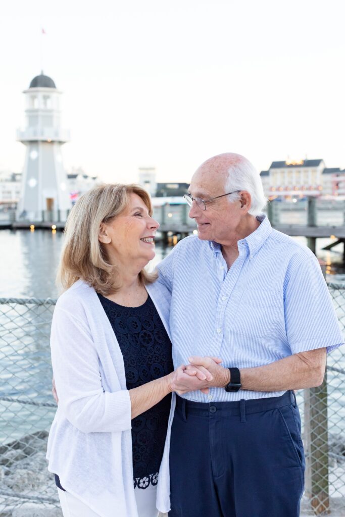 Couple holds hands and smiles at each other for their 40th anniversary at Beach Club at Disney Resort in Orlando Florida