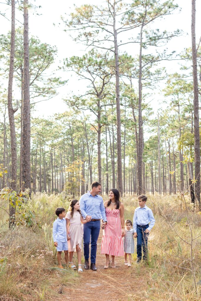 Family walking and holding hands in field at Wekiva Springs State Park for their family photos