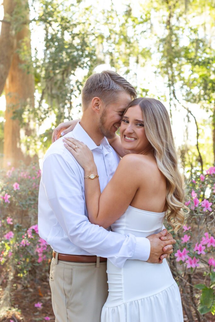Couple snuggles and smiles for their engagement photos at Kraft Azalea Garden in Winter Park, Florida