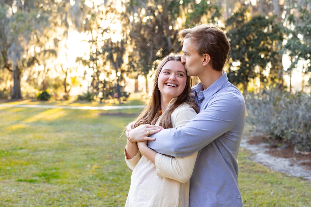 Couple cuddles and smiles after their proposal for their engagement photos at Kraft Azalea Park in Winter Park, Florida